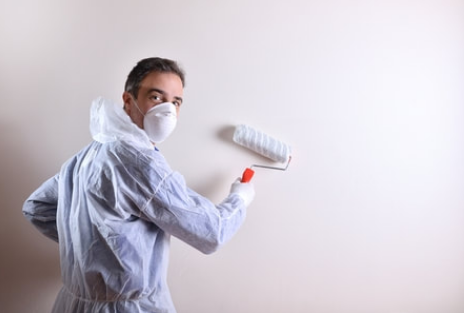 Professional painter member of the Magog Painting team. The man wears protective equipment such as a mask and a coverall.